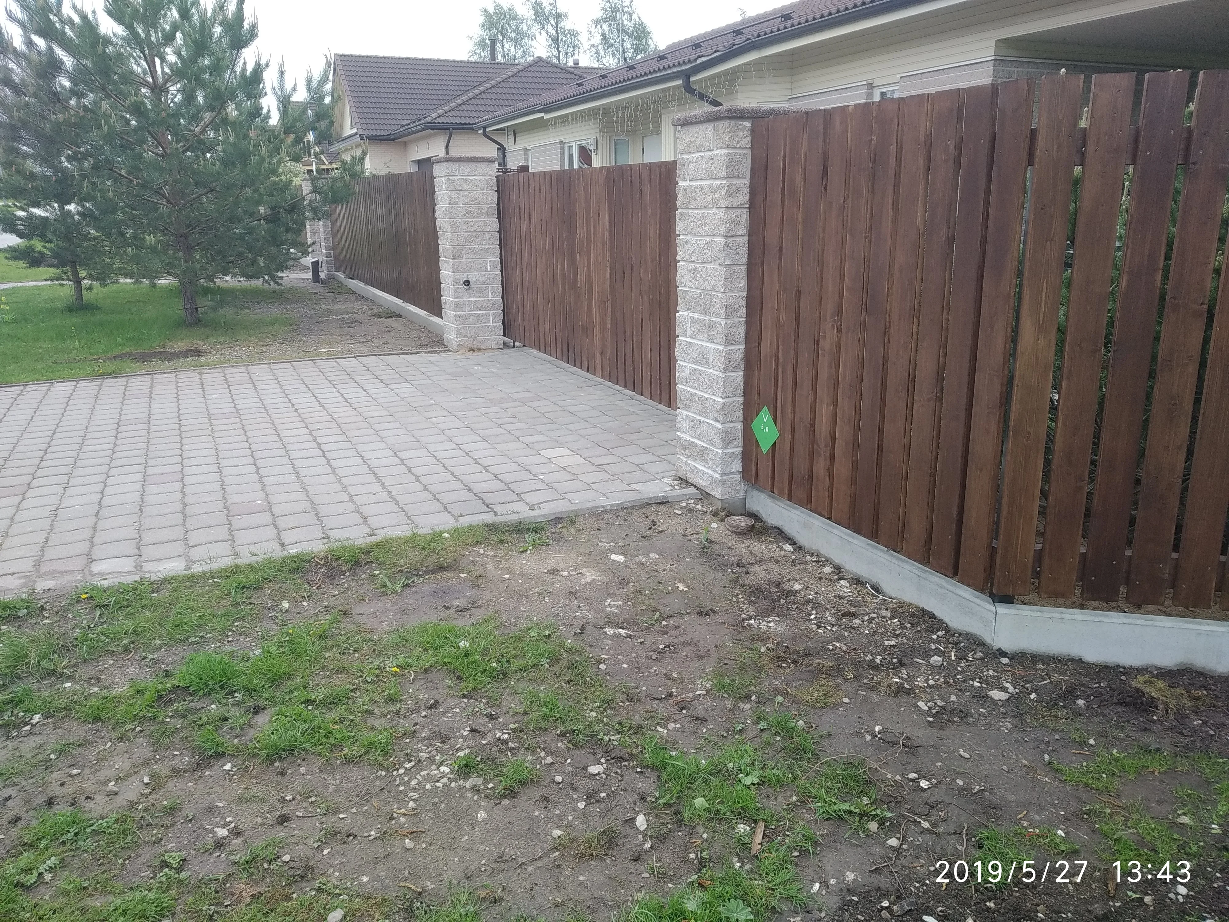 Kivipost - heledad kiviposti vahele paigaldatud pruun puitlaudis eramajal