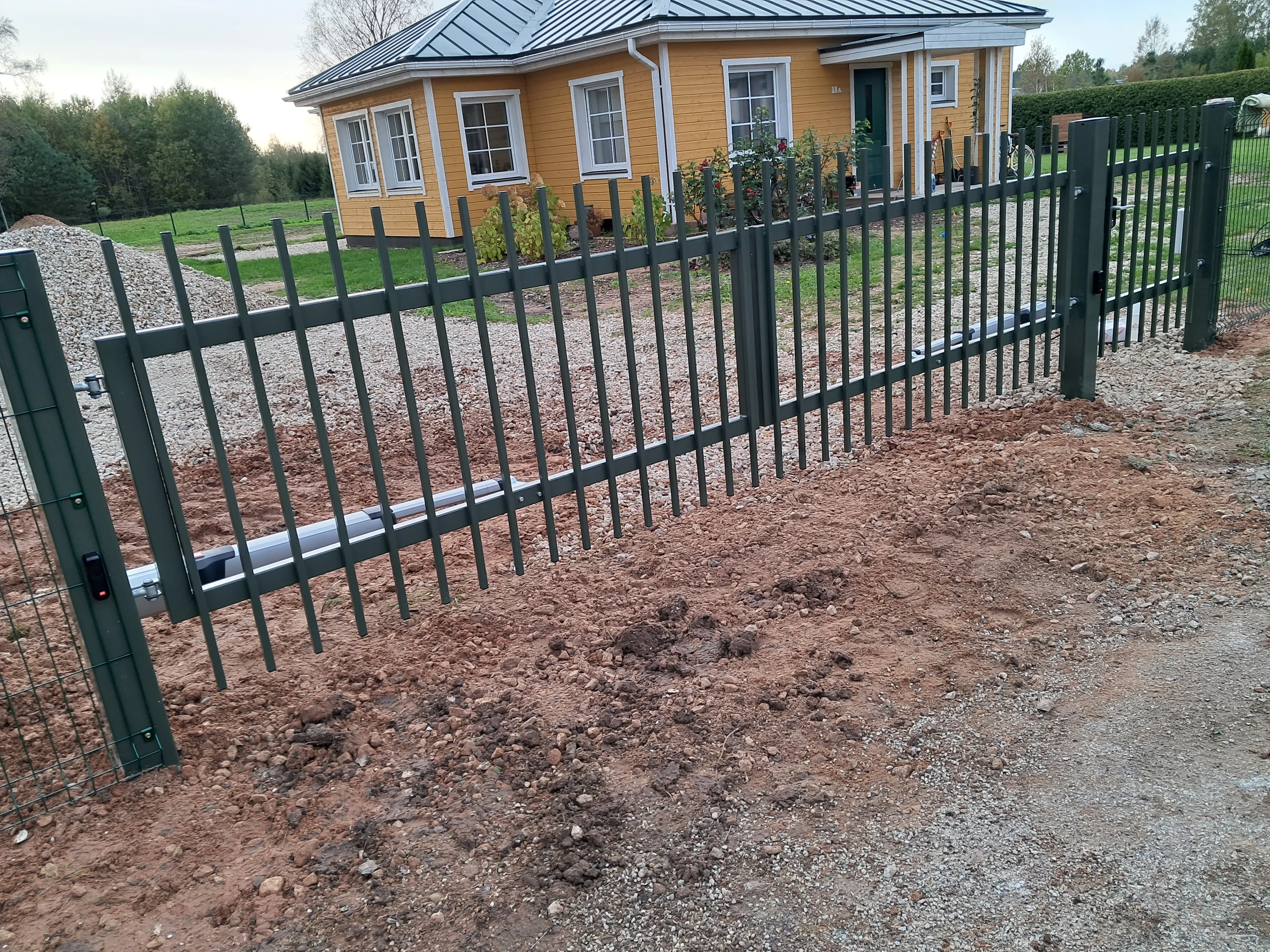 Metallaed - antratsiithall metallvarbaed libiseva väravaga kollase maja ees