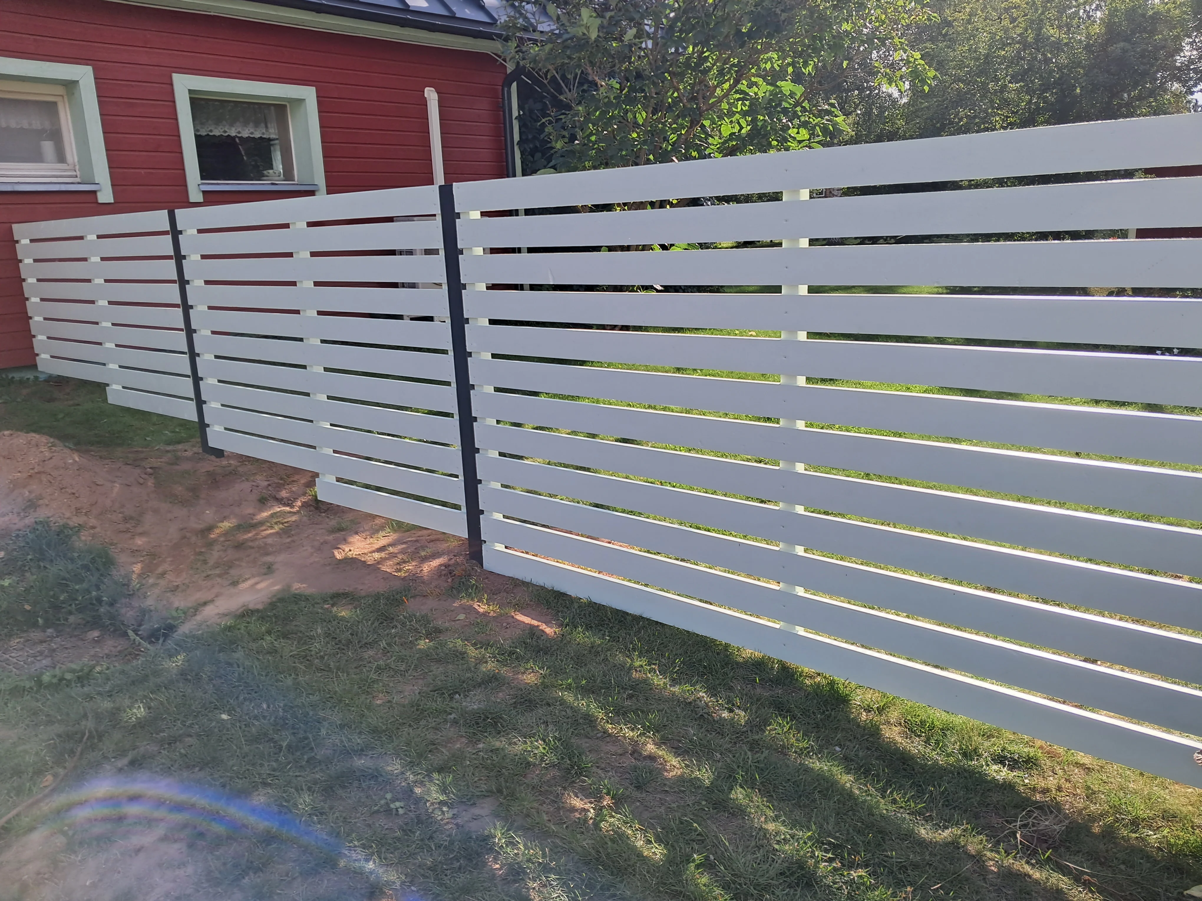 Puitaed - horisontaalne valge laudis metalpostidel eramu aias