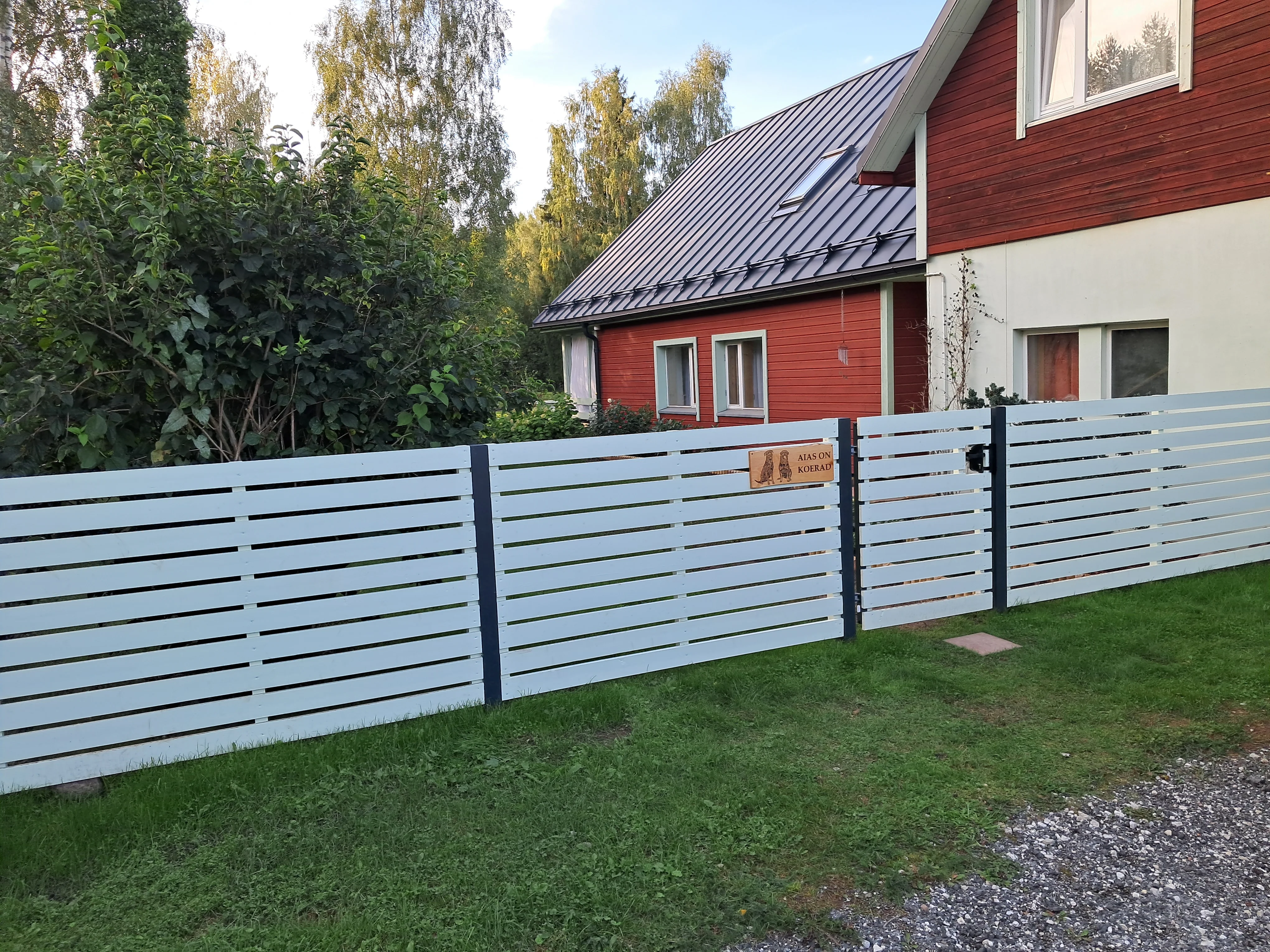 Puitaed - horisontaalne valge laudis tumehallide postidega eramu hoovis