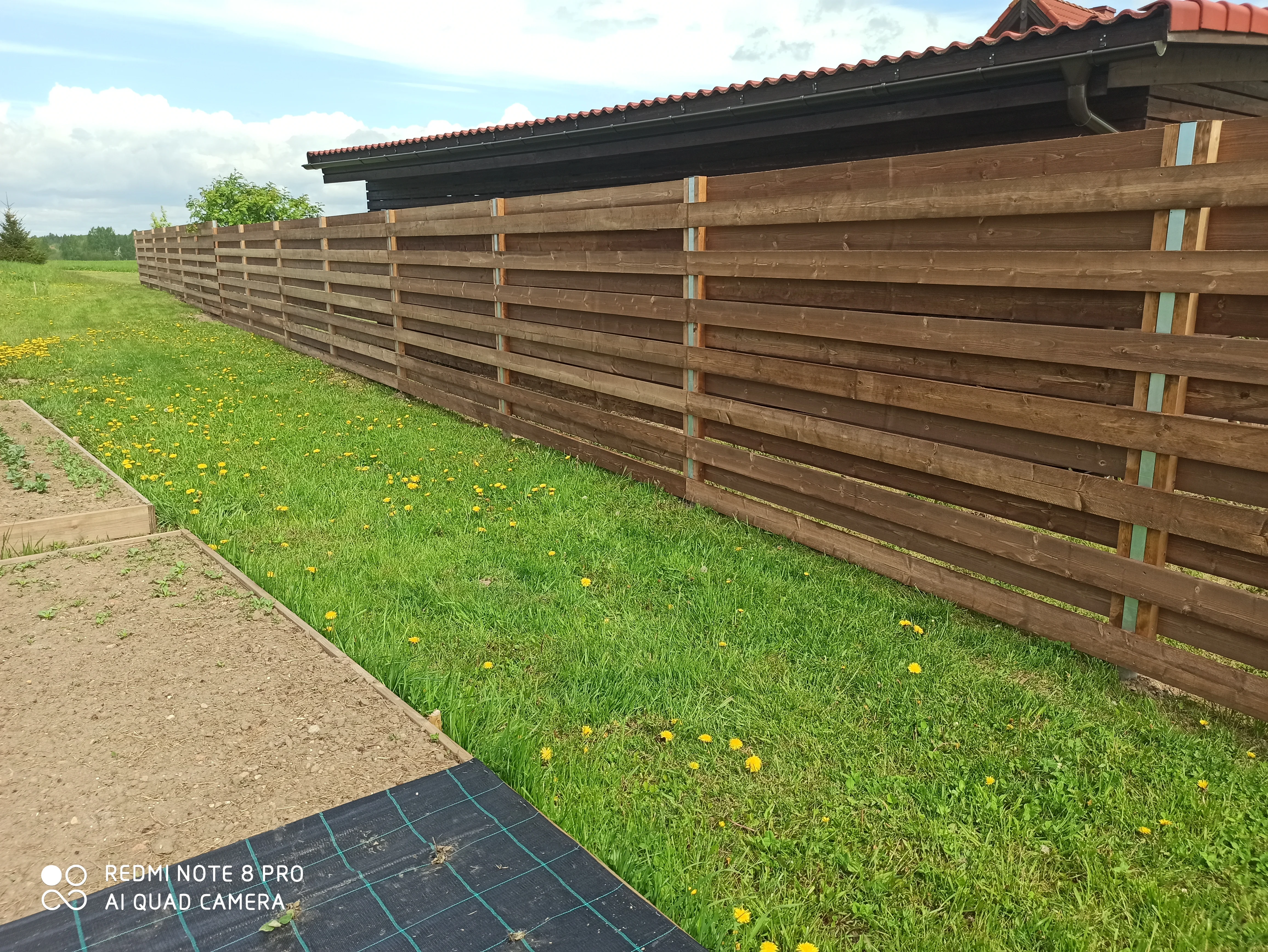 Puitaed - horisontaalne pruun laudis metalpostidel aia ääres