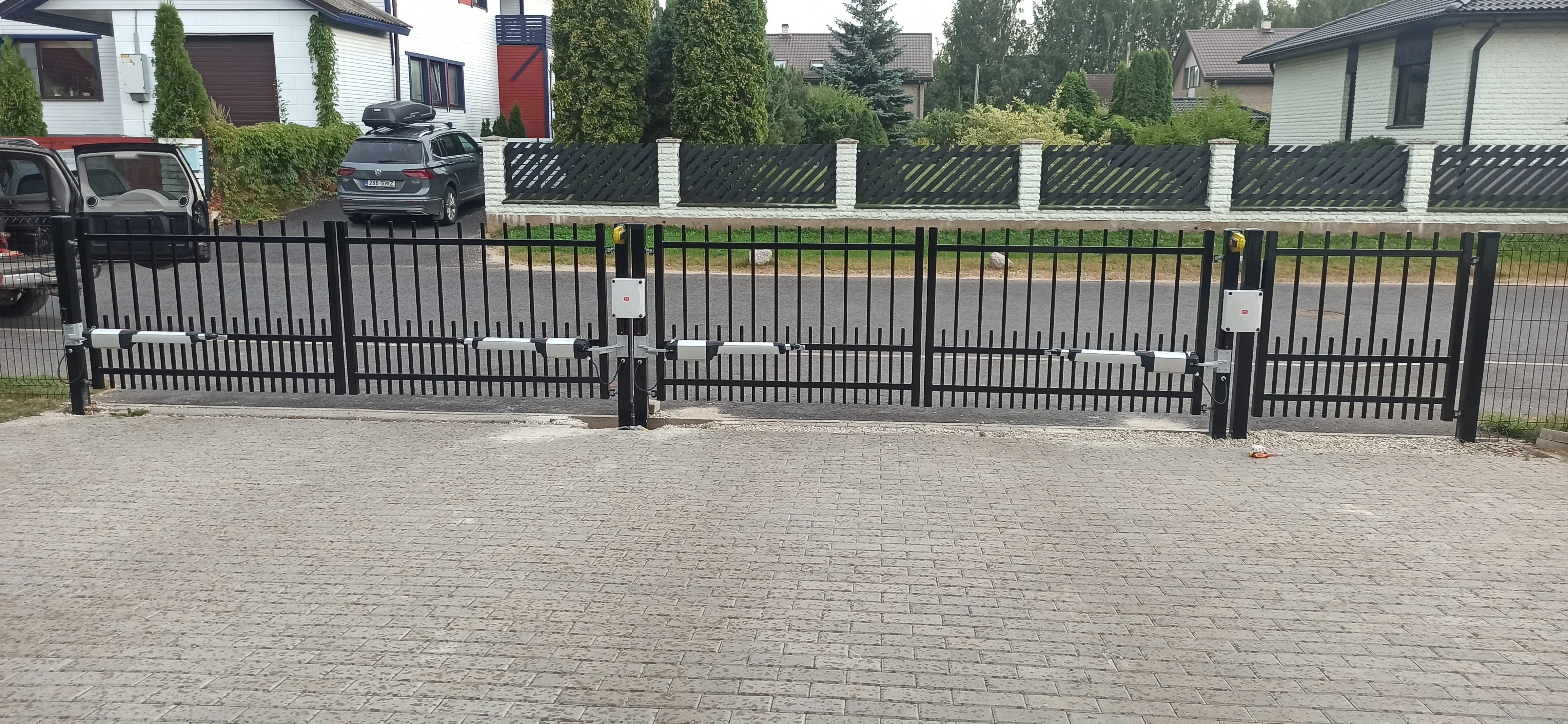 Varav - must metallvarbaed tiibvärav automaatikamootoritega kivipostide vahel